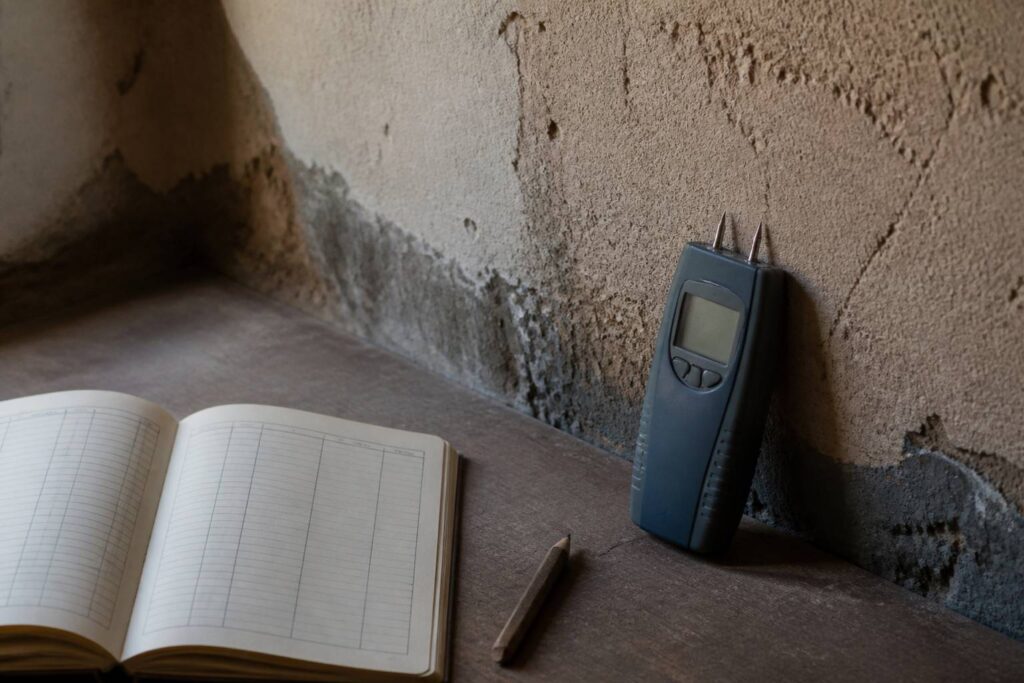 Humidimètre à pointes contre un mur avec carnet de relevé