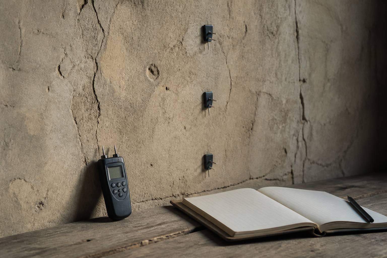 Humidimètre posé contre un mur avec carnet de relevé